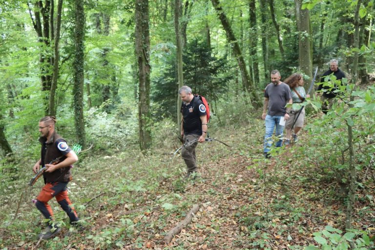 Bogenschützen wandern hintereinander einen bewaldeten Hang hinauf