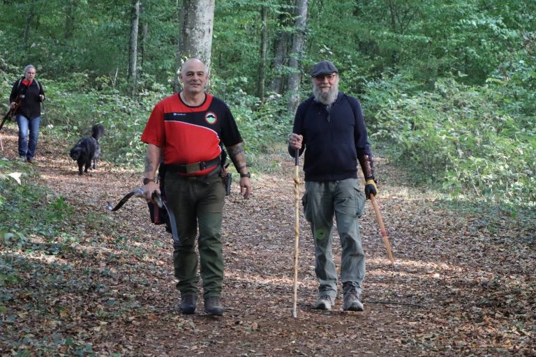 Zwei Bogenschützen mit Langbögen kommen einen Waldweg entlang