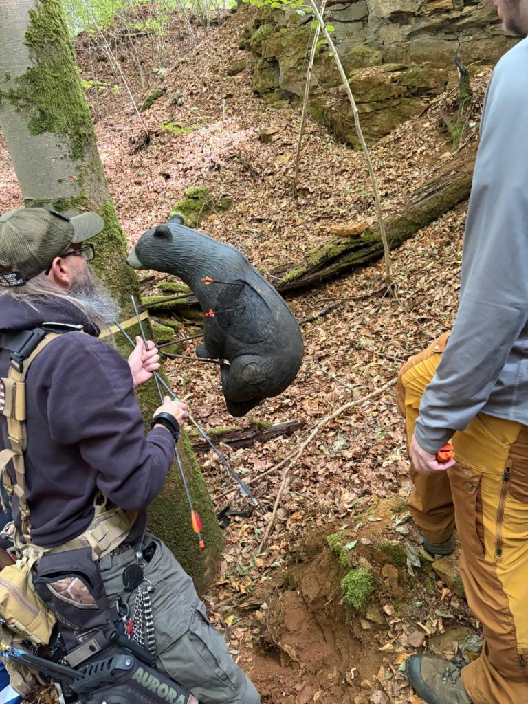 Bogenschütze am 3D-Bärenziel an einem Baum auf dem Waldhang