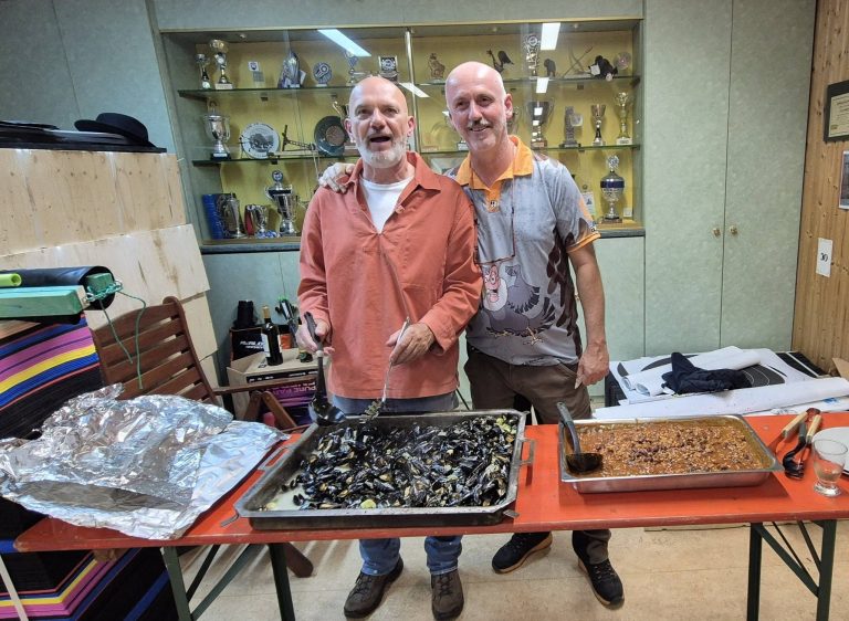 Zwei Männer stehen lachend hinter dem Buffet mit Muscheln in der Vereinsküche