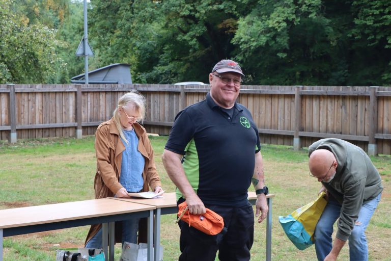 Lächelnder Mann mit orangefarbenem Preis am Preistisch auf der Wiese