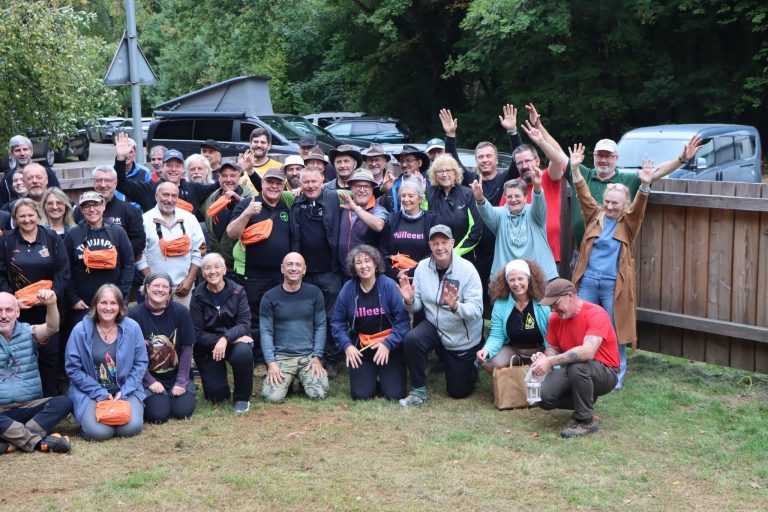 Winkende Teilnehmer beim Gruppenfoto auf der Wiese am Vereinsgelände
