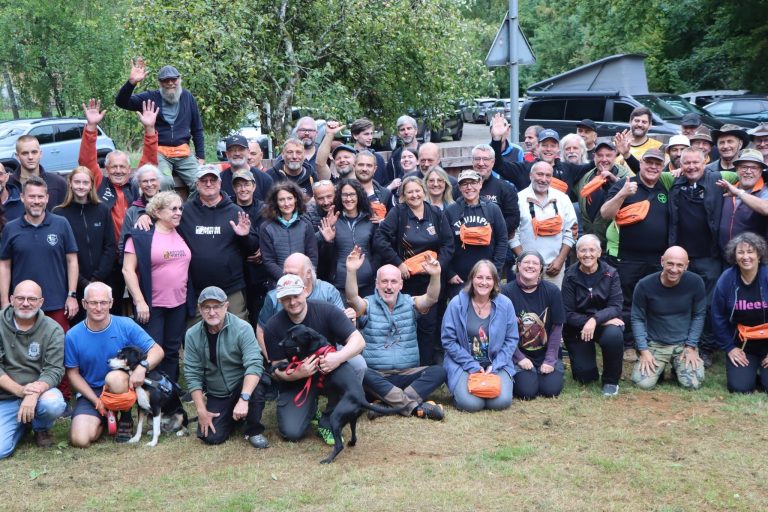 Gruppenfoto zahlreicher Teilnehmer auf der Wiese, viele halten orangefarbene Preise