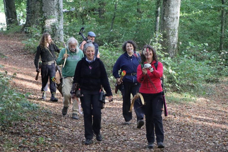 Gut gelaunte Gruppe von Bogenschützen kommt über einen Waldweg zurück