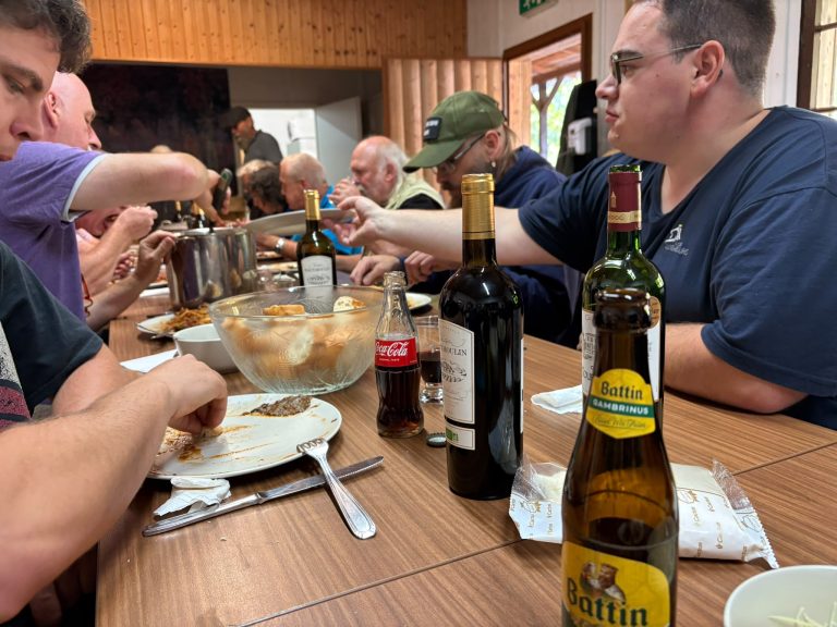Teilnehmer essen gemeinsam an einem Tisch mit Getränken und Brot