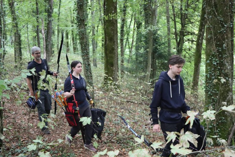 Drei Bogenschützen, darunter ein Jugendlicher, gehen durch den Wald