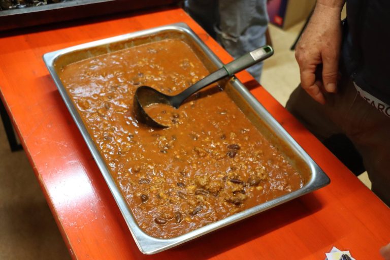 Blech mit herzhaftem Eintopf und Schöpfkelle auf dem Buffet