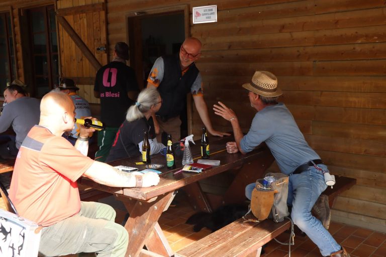 Teilnehmer sitzen auf der überdachten Terrasse am Holztisch und unterhalten sich