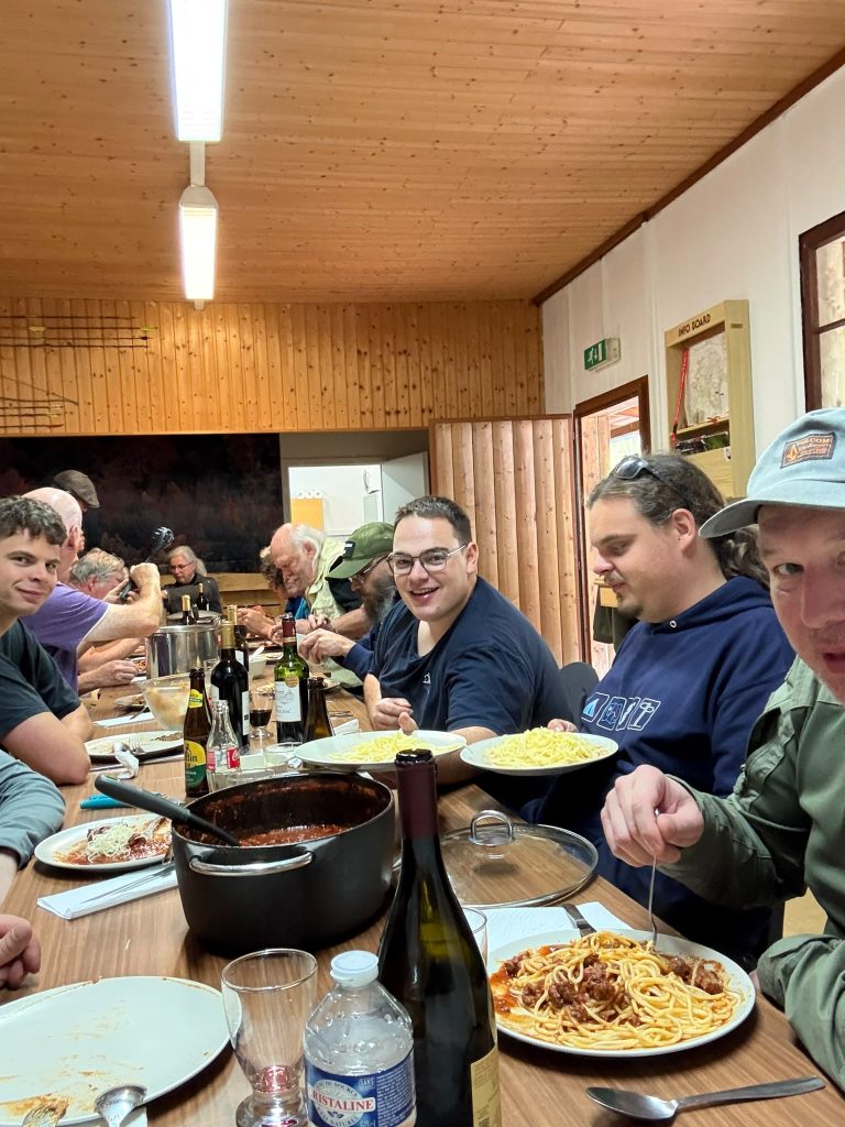 Junge Teilnehmer essen Nudeln und Muscheln an einem Tisch im Vereinshaus