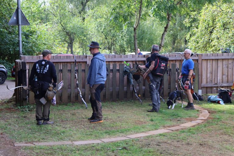 Bogenschützen mit Bögen auf der Wiese vor dem Holzzaun am Vereinsgelände