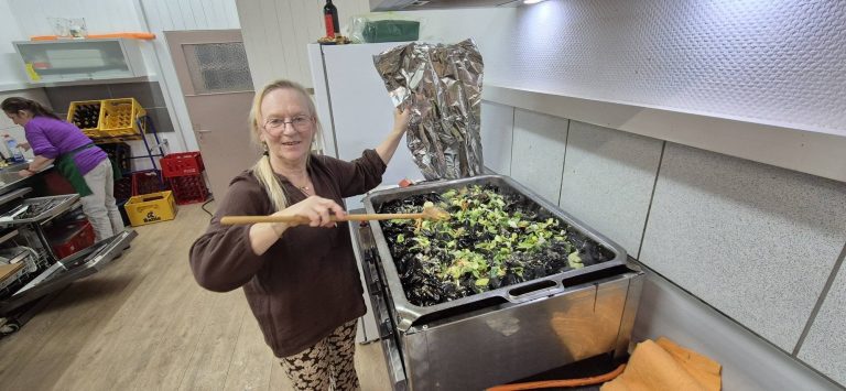 Frau rührt in der Vereinsküche eine große Pfanne mit Muscheln um