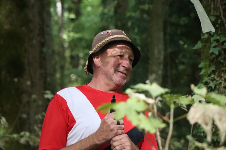 Lachender Mann mit Hut und rot-weißem Shirt im Wald