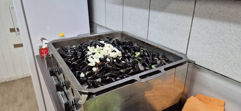 Große Pfanne mit Miesmuscheln und Zwiebeln in der Vereinsküche