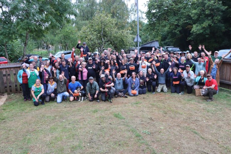 Gruppenfoto aller Teilnehmer auf der Wiese vor dem Vereinsgelände, viele winken