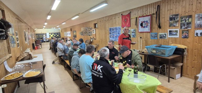 Teilnehmer sitzen an einer langen Tafel im Vereinshaus beim Essen