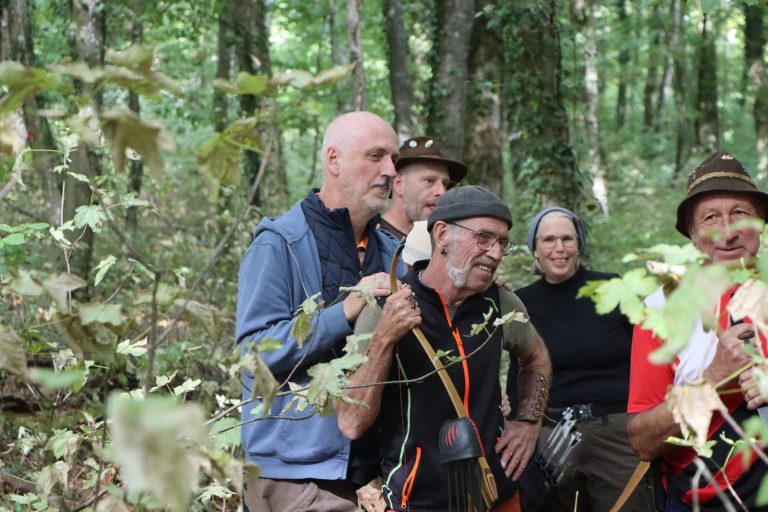 Fröhliche Gruppe von Bogenschützen mit Hüten posiert im Wald