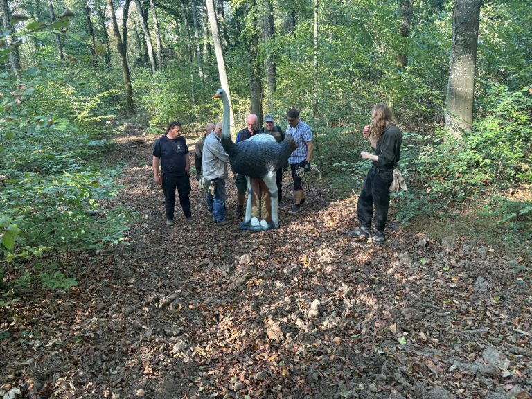 Gruppe von Bogenschützen steht um ein 3D-Straußenziel auf einem Waldweg