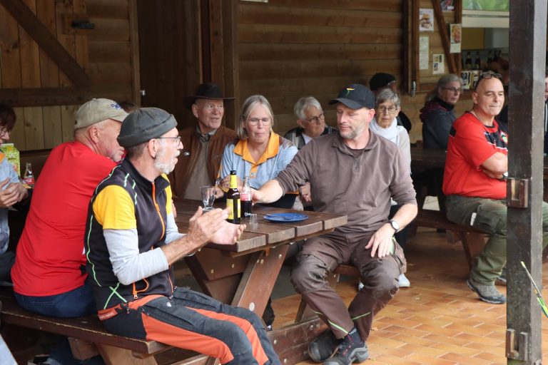 Teilnehmer sitzen gesellig an Holztischen im Vereinshaus
