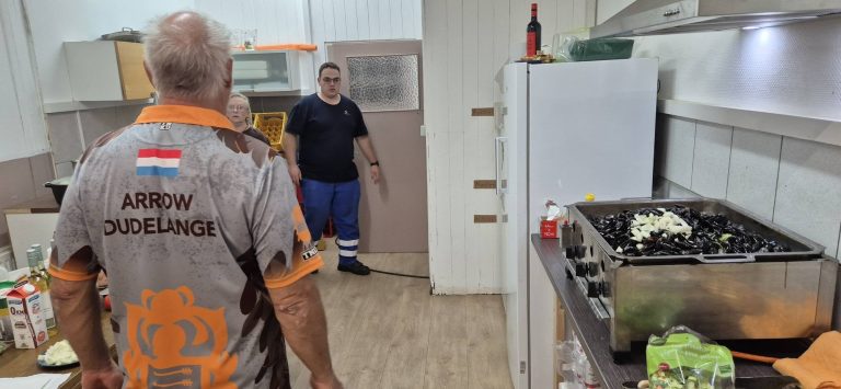 Mann im Vereinstrikot von Arrow Dudelange in der Küche vor einer großen Pfanne