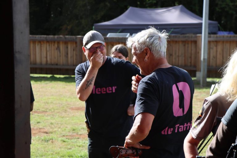 Zwei Männer in schwarzen T-Shirts lachen gemeinsam auf dem Vereinsgelände