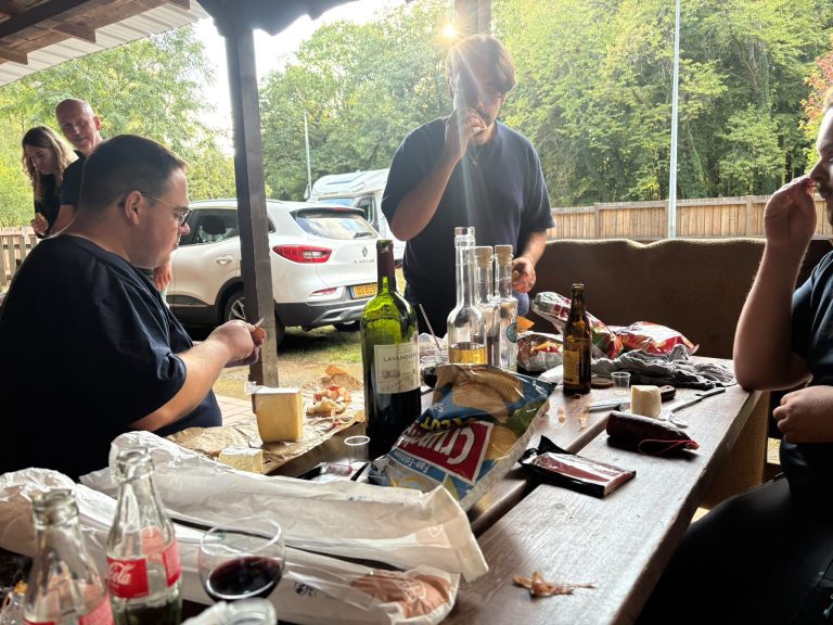 Teilnehmer sitzen mit Getränken und Snacks am Tisch auf der Terrasse