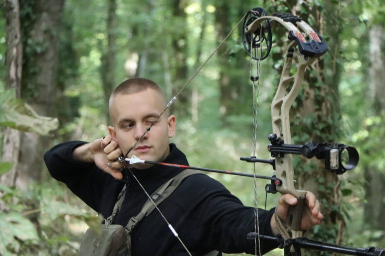 Junger Bogenschütze spannt einen Compoundbogen, Nahaufnahme im Wald