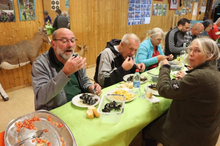 Teilnehmer essen Muscheln an einer Tafel im Vereinshaus, vorne eine Schale mit Tomaten
