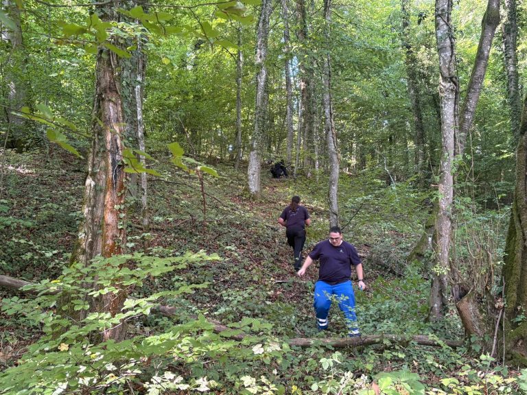 Zwei Bogenschützen steigen einen bewachsenen Waldhang hinauf