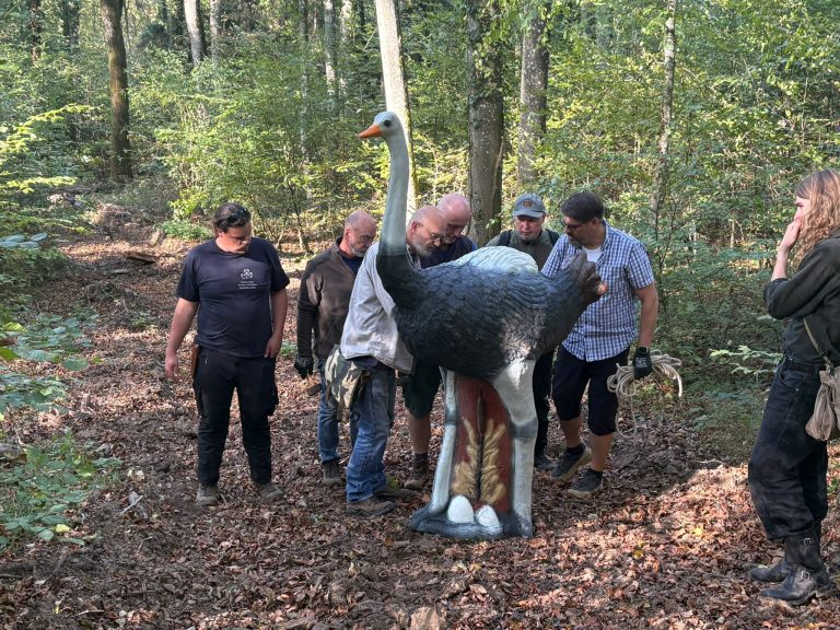 Bogenschützen stehen um ein großes 3D-Straußenziel auf dem Waldboden