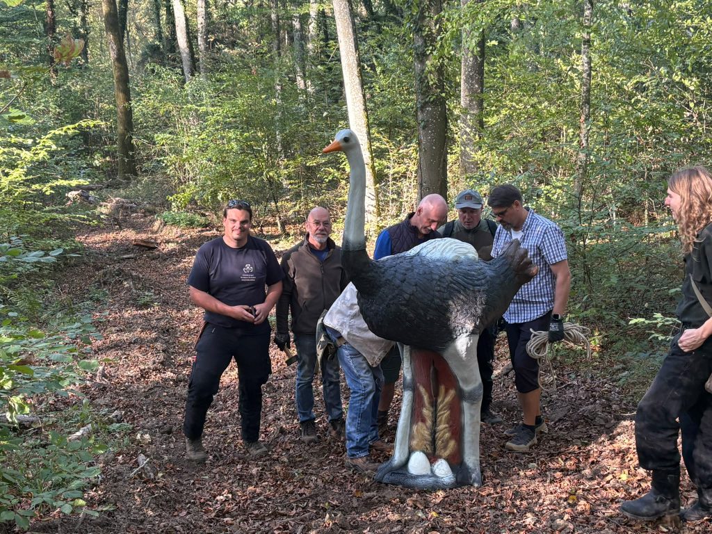 Bogenschützen stehen um ein 3D-Straußenziel im Wald und ziehen ihre Pfeile