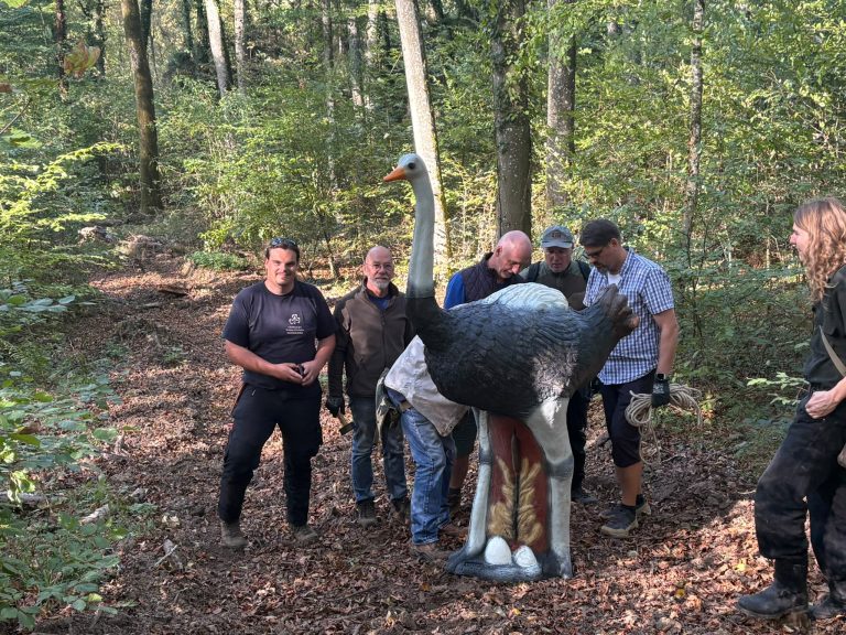 Bogenschützen stehen um ein 3D-Straußenziel im Wald und ziehen ihre Pfeile