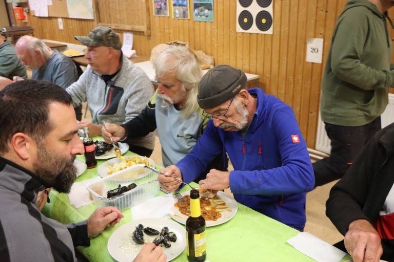 Teilnehmer essen Muscheln und Pommes an einer grün gedeckten Tafel