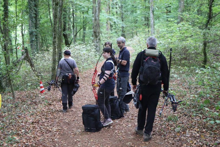 Bogenschützen mit Ausrüstung warten auf einem Waldweg an einem Leitkegel