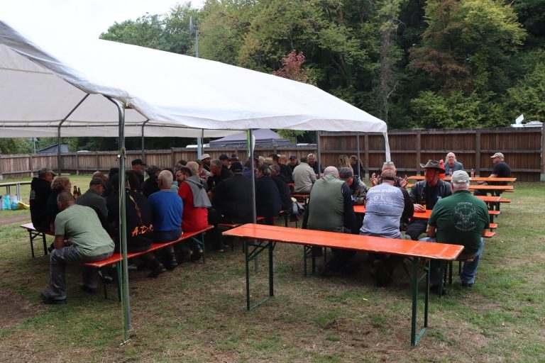 Teilnehmer sitzen an Biertischen unter einem weißen Festzelt