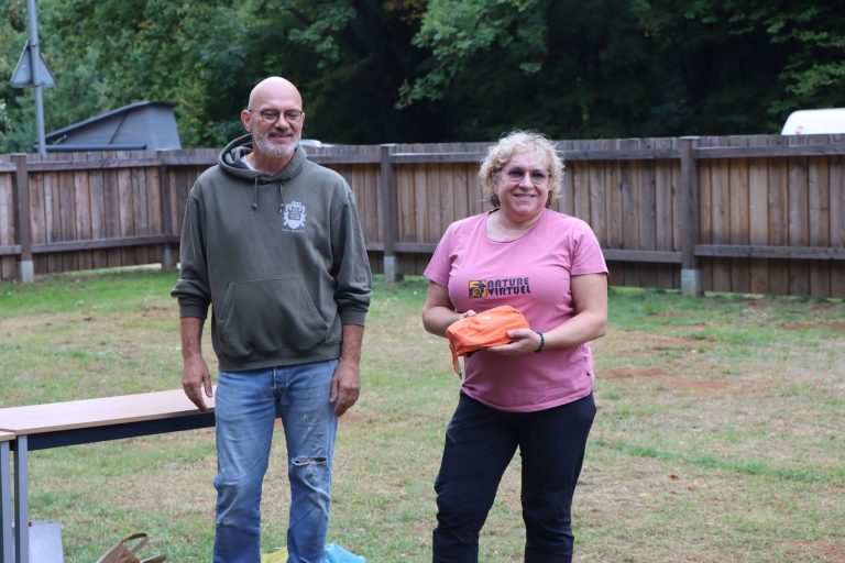 Mann im grauen Pullover und Frau im pinken T-Shirt mit orangefarbenem Preis