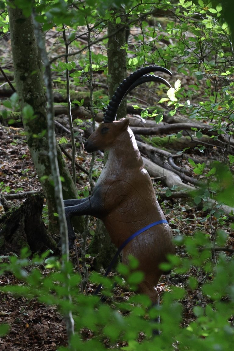 Aufgerichteter 3D-Steinbock mit langen Hörnern zwischen Bäumen