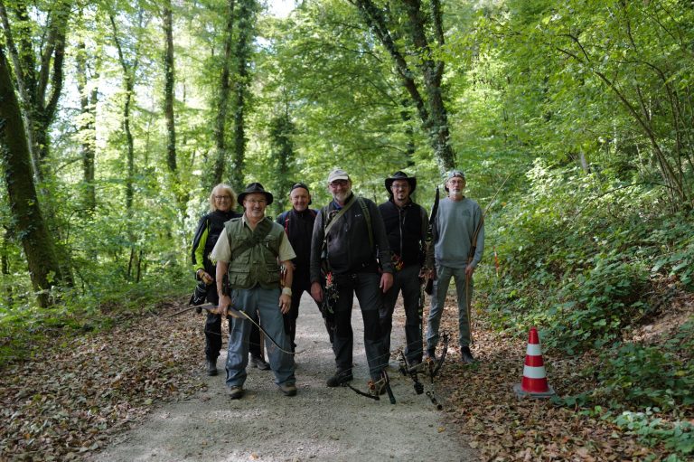 Gruppe von Bogenschützen mit Bögen und Hüten steht auf einem Waldweg