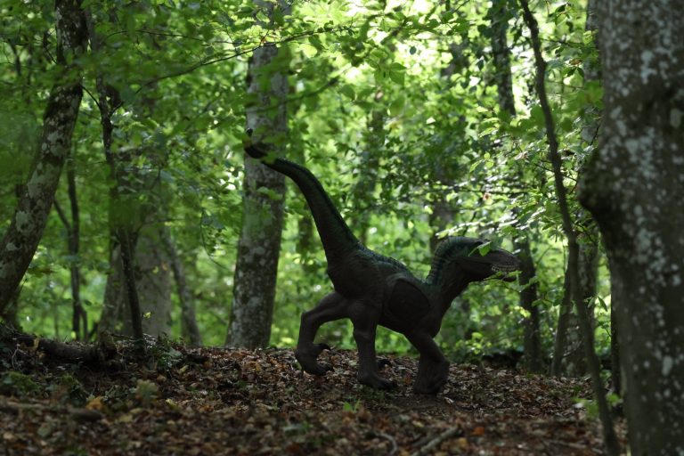 3D-Ziel eines zweibeinigen Raubsauriers zwischen Bäumen im Wald