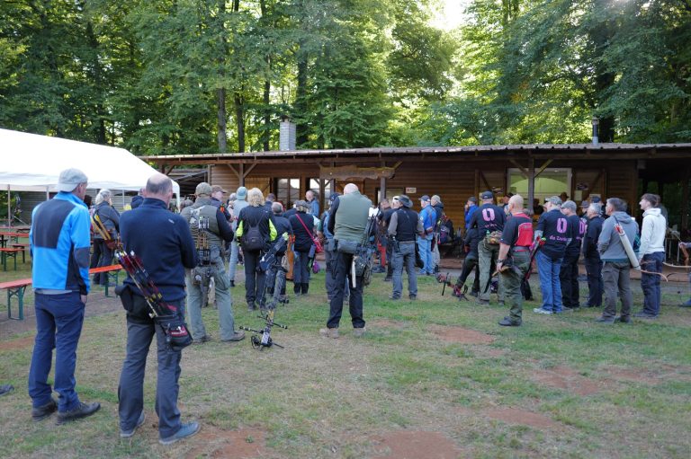 Gruppe von Bogenschützen versammelt sich auf der Wiese vor dem Vereinsgebäude
