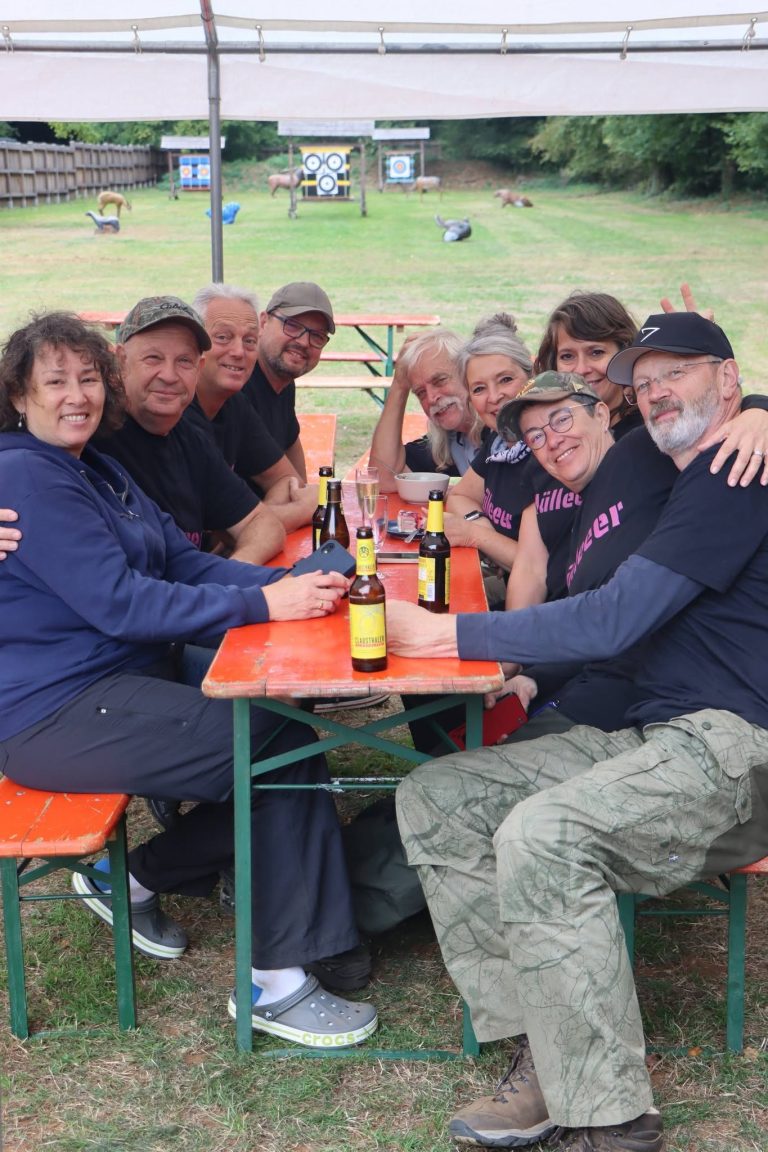 Gruppe von Teilnehmern sitzt lachend mit Getränken am Biertisch