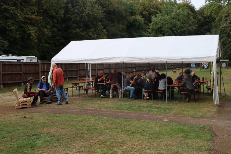 Weißes Festzelt mit Teilnehmern an Bierbänken auf der Wiese