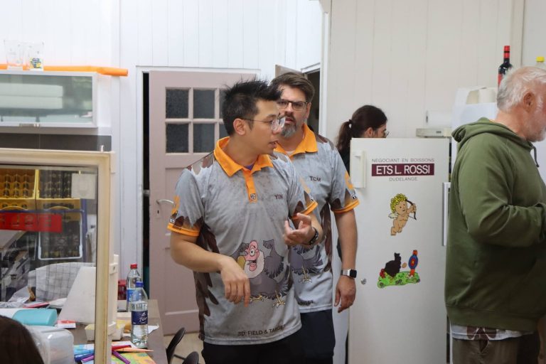 Mitglieder in orange-grauen Vereinstrikots in der Vereinsküche
